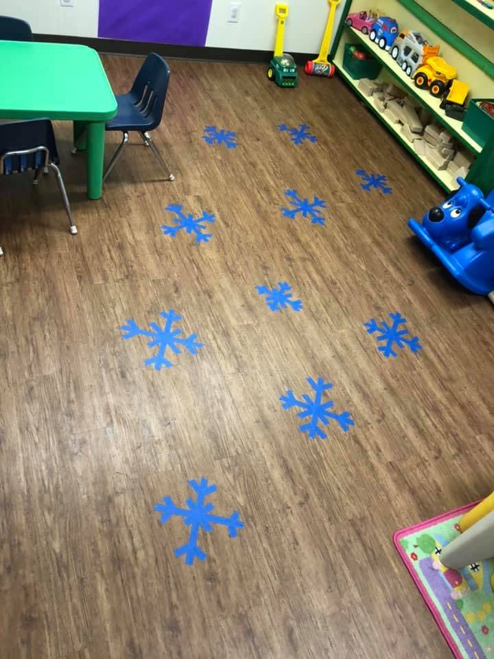 Blue snowflake cutouts on a wooden floor in a classroom
