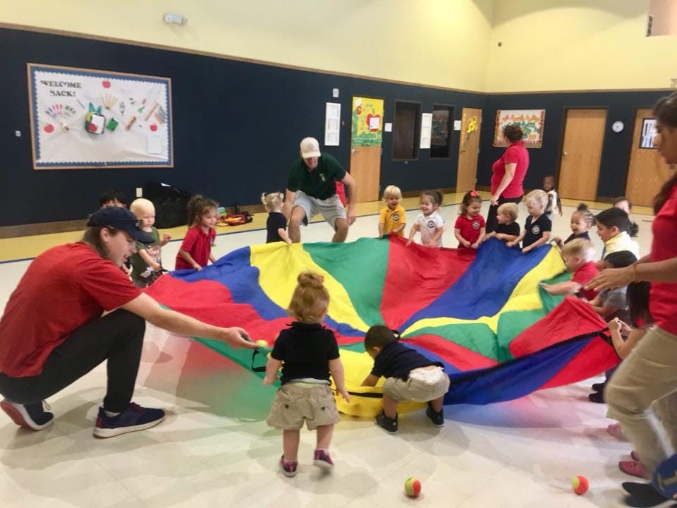 Adults and children playing with a colorful parachute