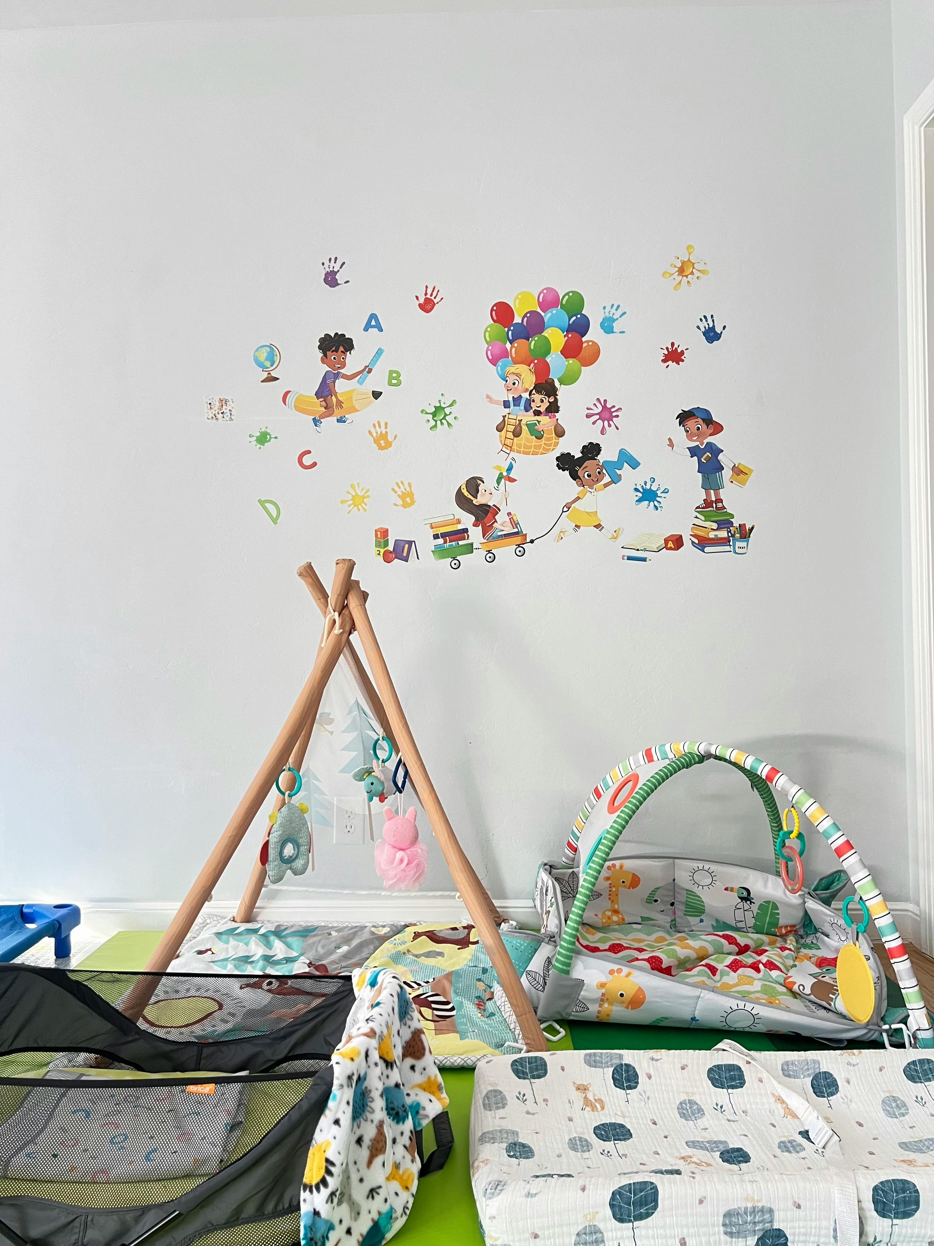 Playroom with wall decals of children and play mats on the floor