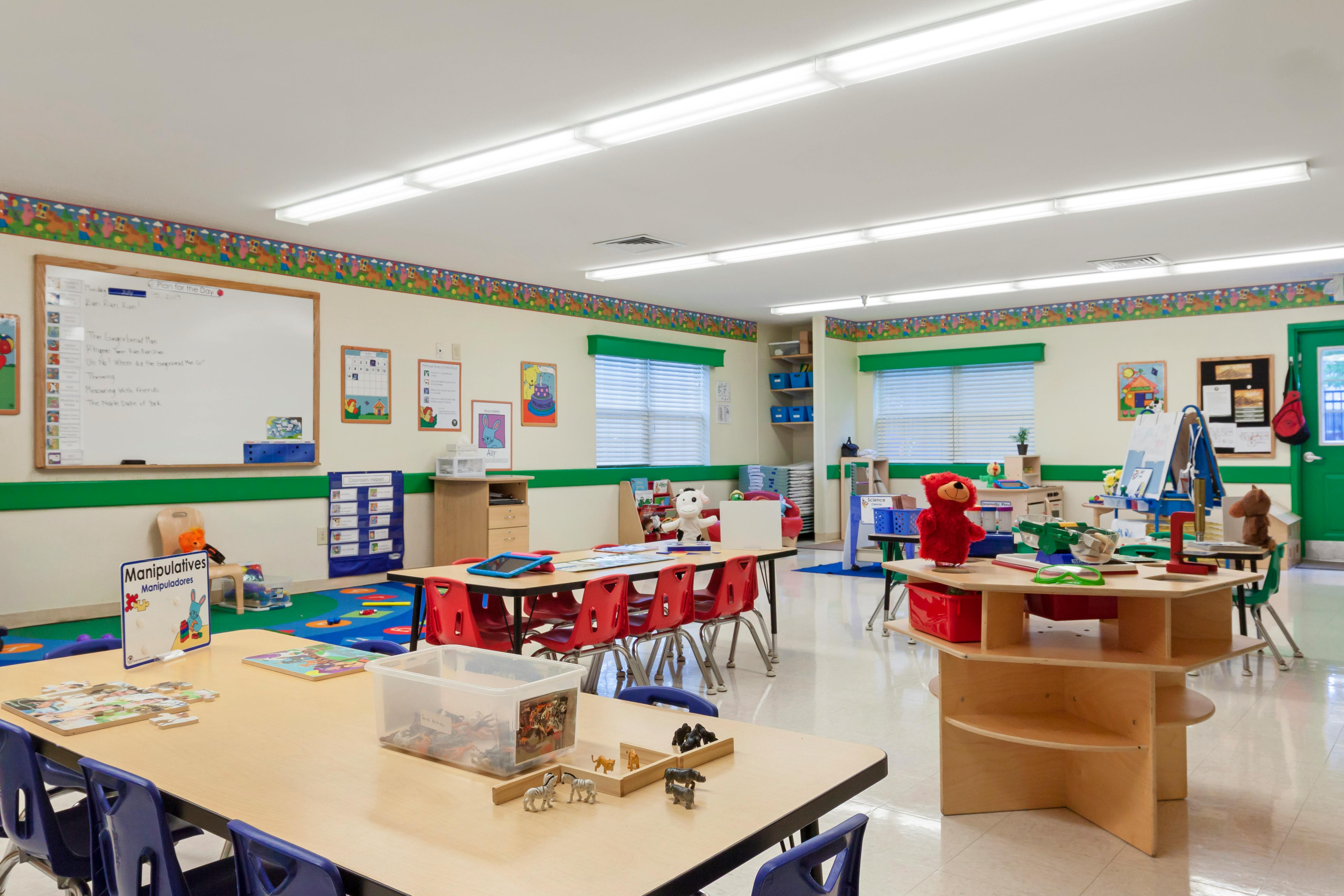 Children's classroom with tables, chairs, toys, and learning materials