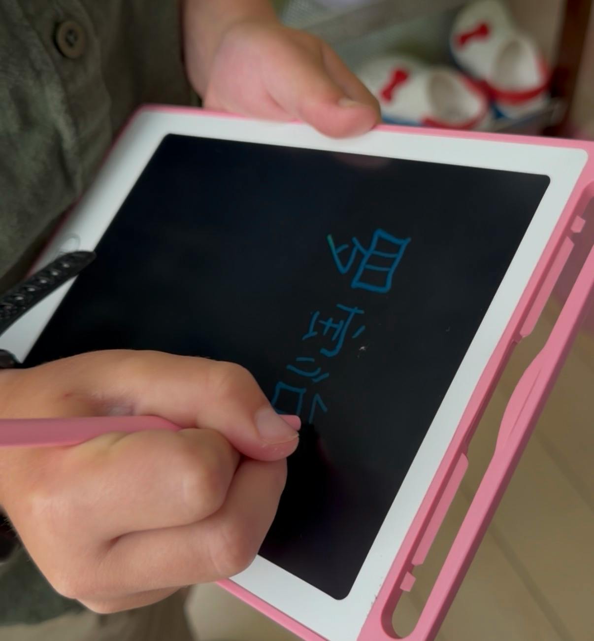 Person writing Chinese characters on a digital drawing tablet with a stylus