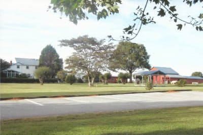 White house and red barn with green lawn and trees