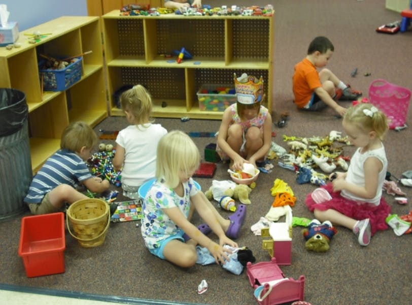 Children playing with toys on the floor in a classroom