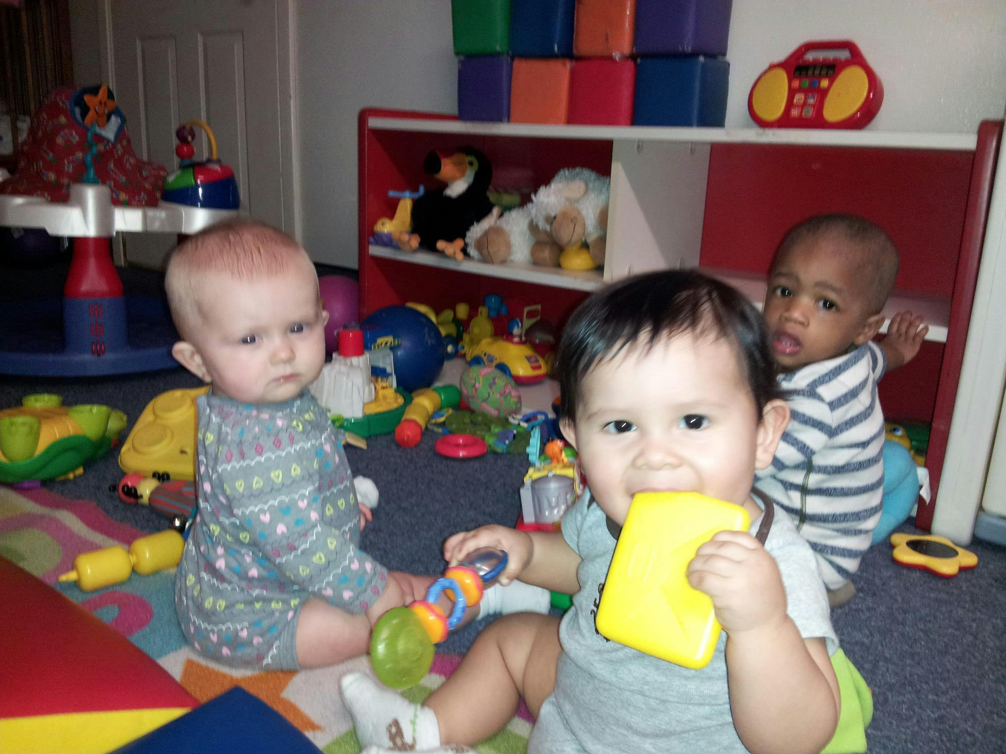 Three babies playing with toys on the floor
