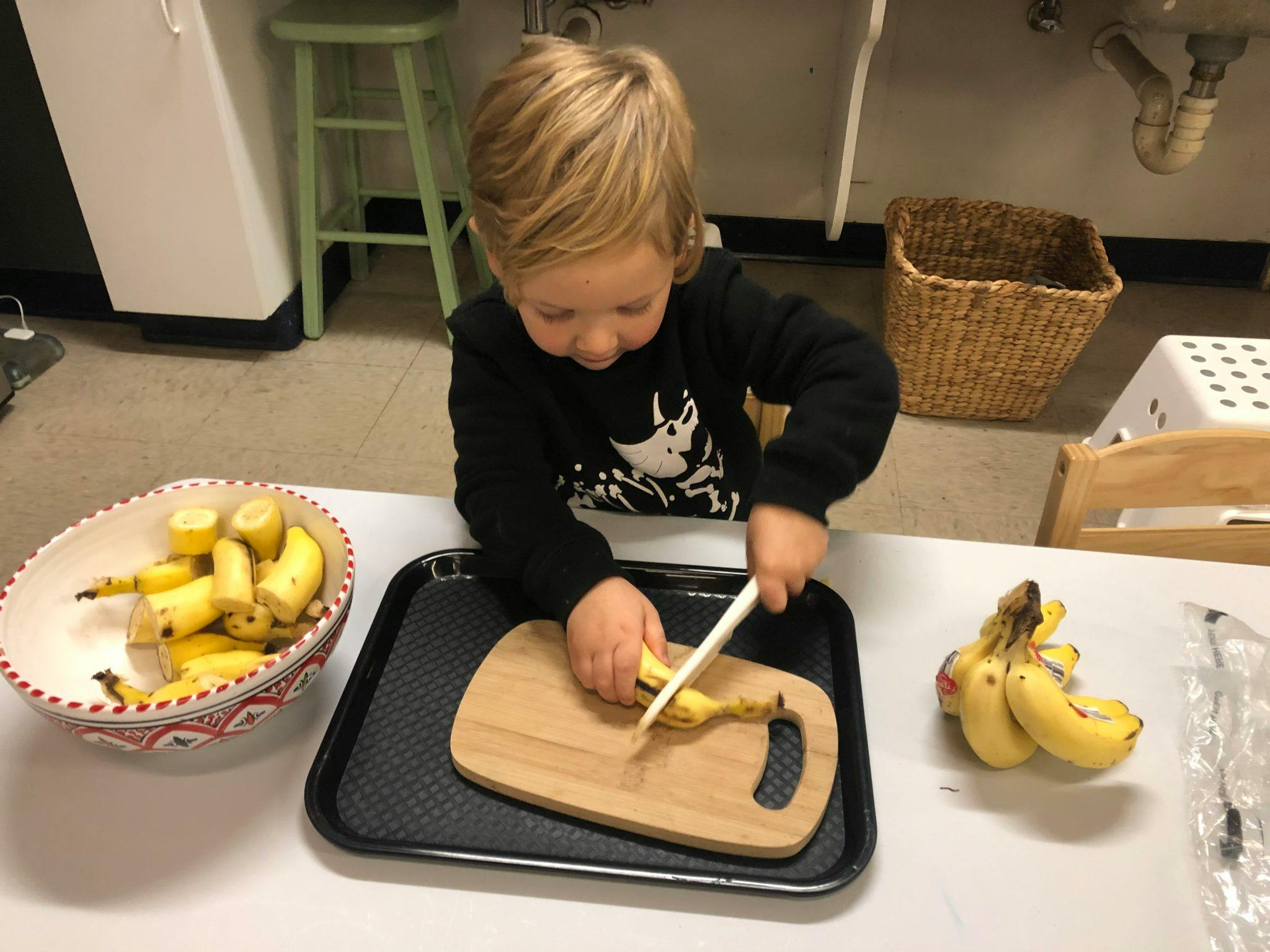 Child cutting a banana on a cutting board