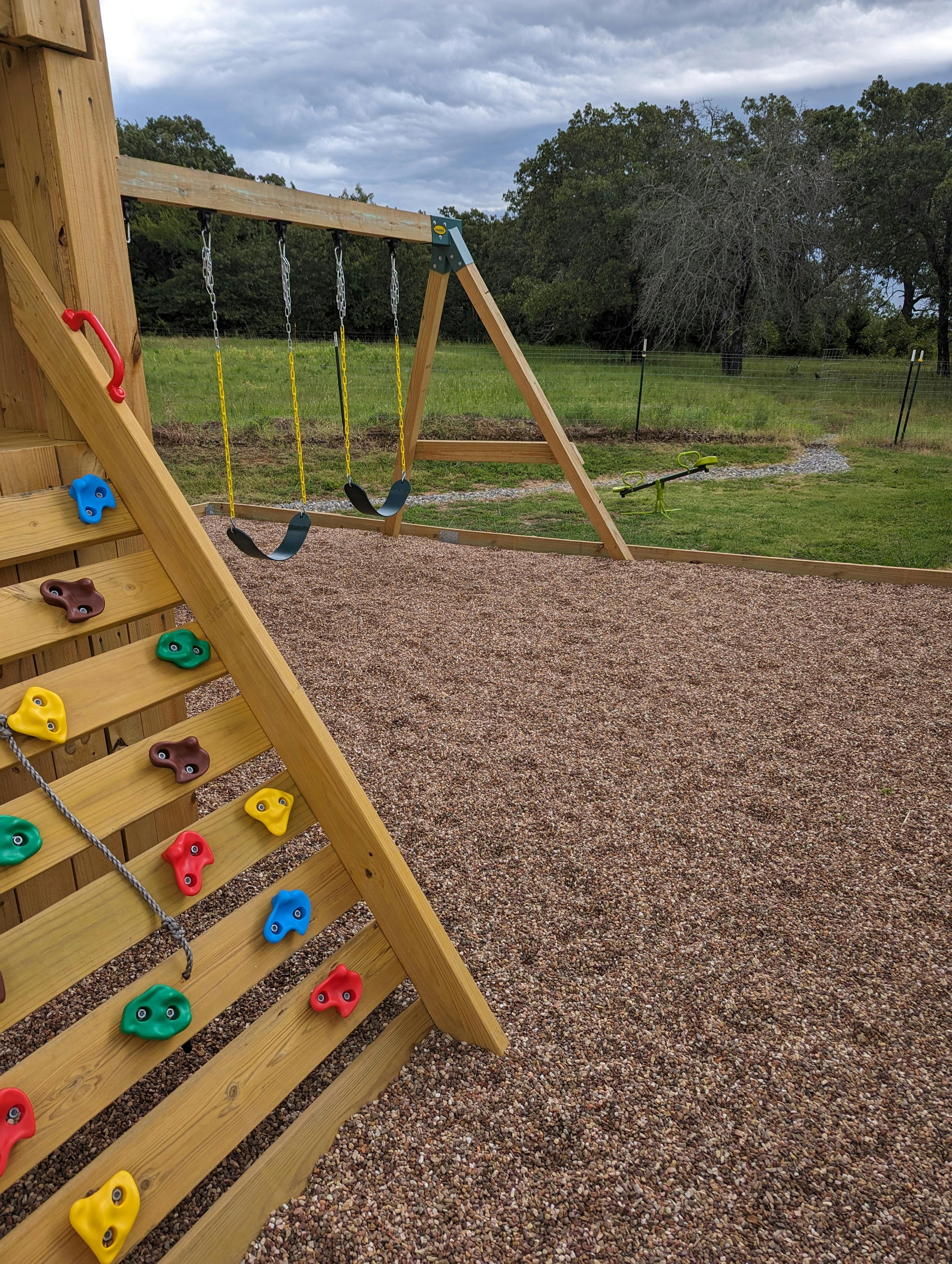 Playground with a wooden climbing wall and swing set