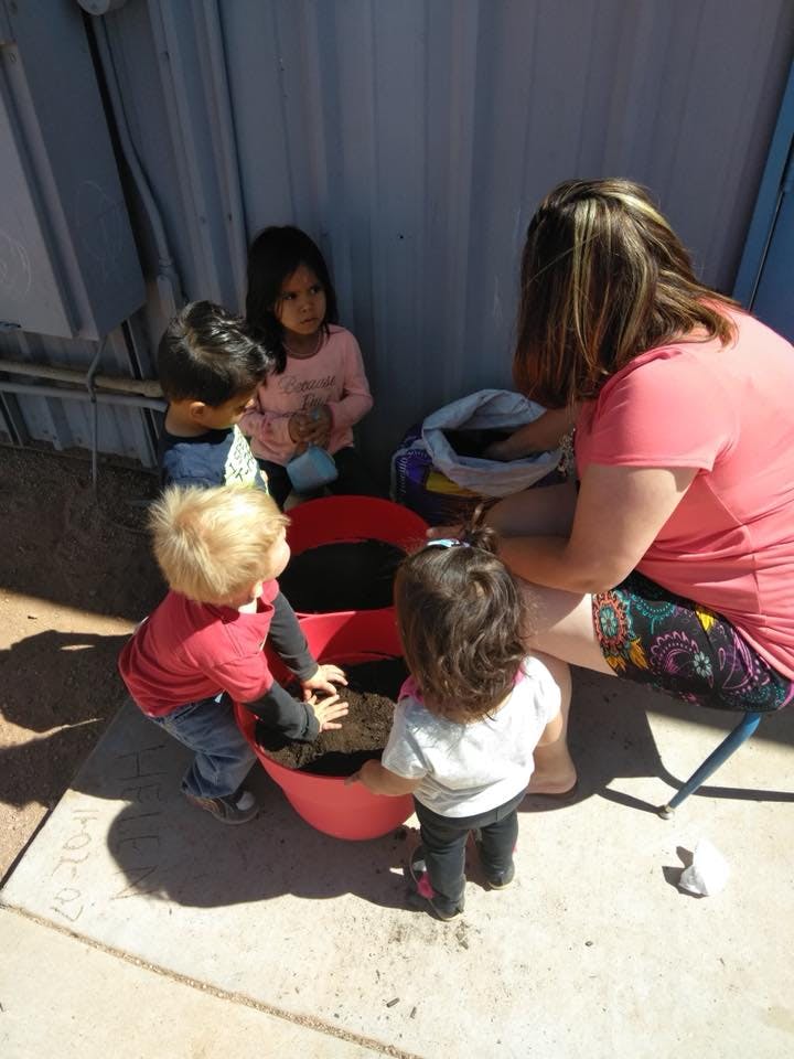 Adult and children planting in a red tiered planter