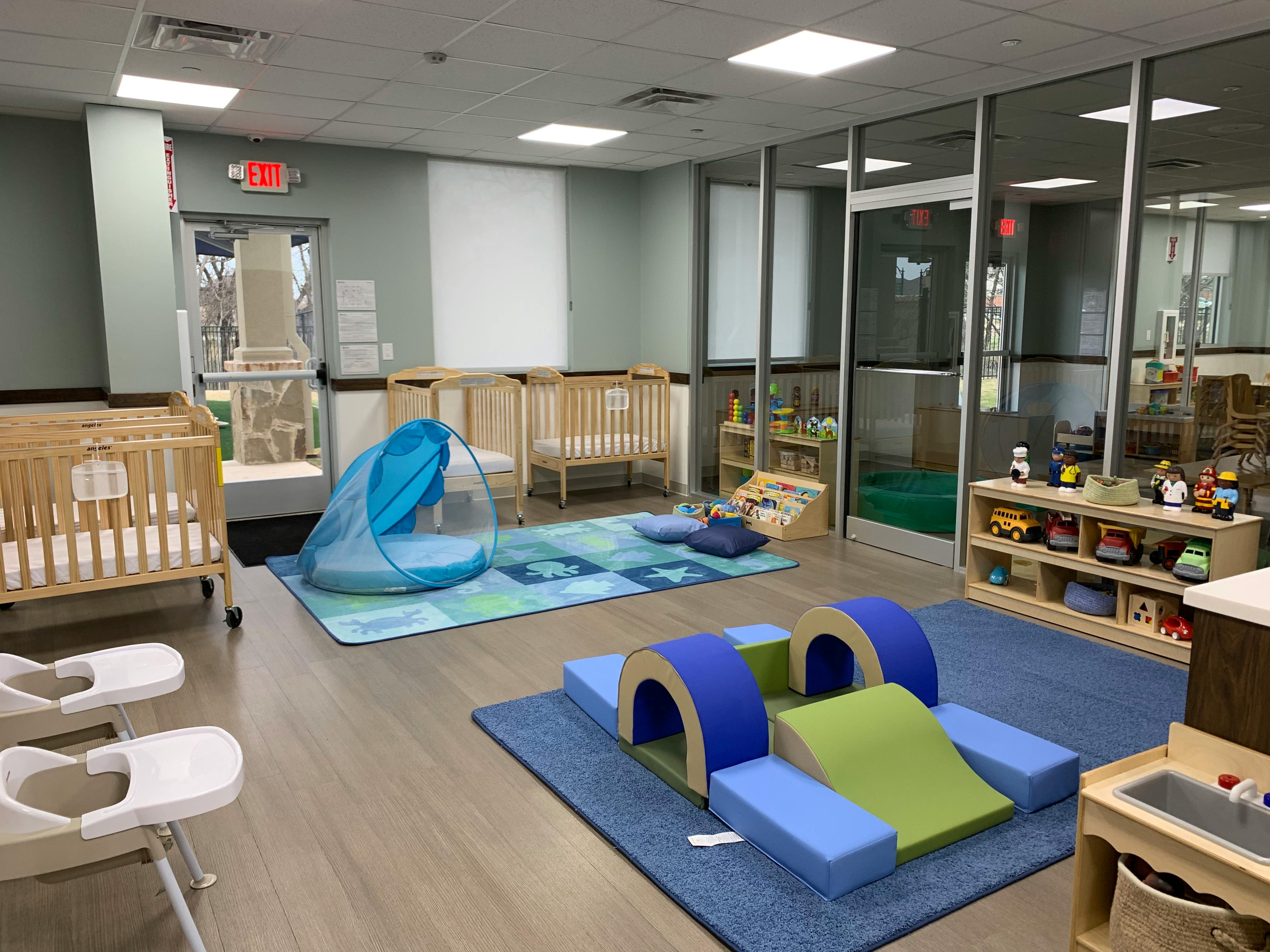 Daycare room with cribs, play mats, and soft play equipment