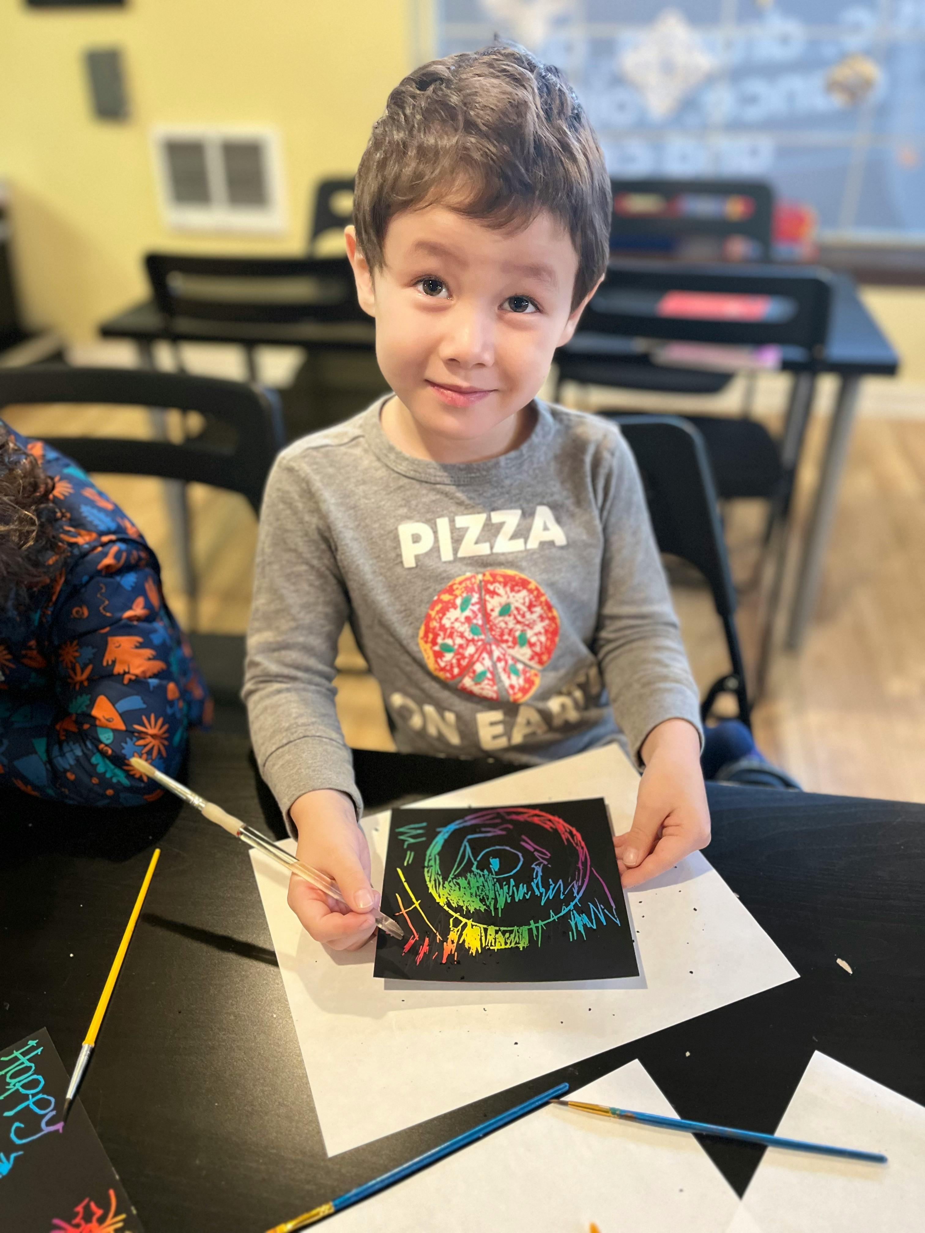 Child scratching a colorful design onto a black paper