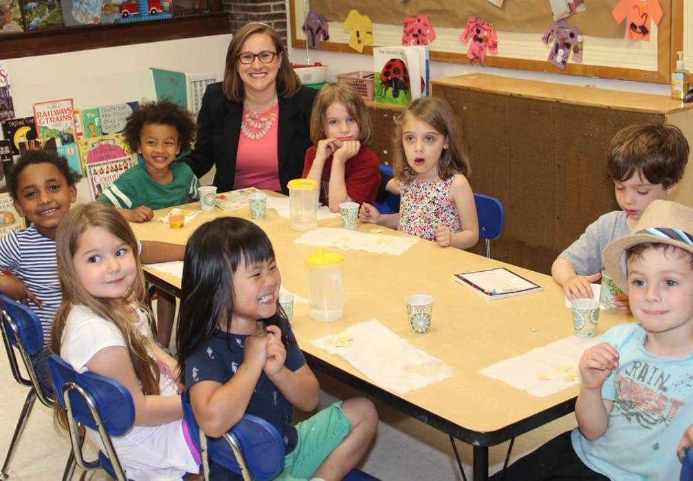 Adult and multiple children sitting at a table in a classroom