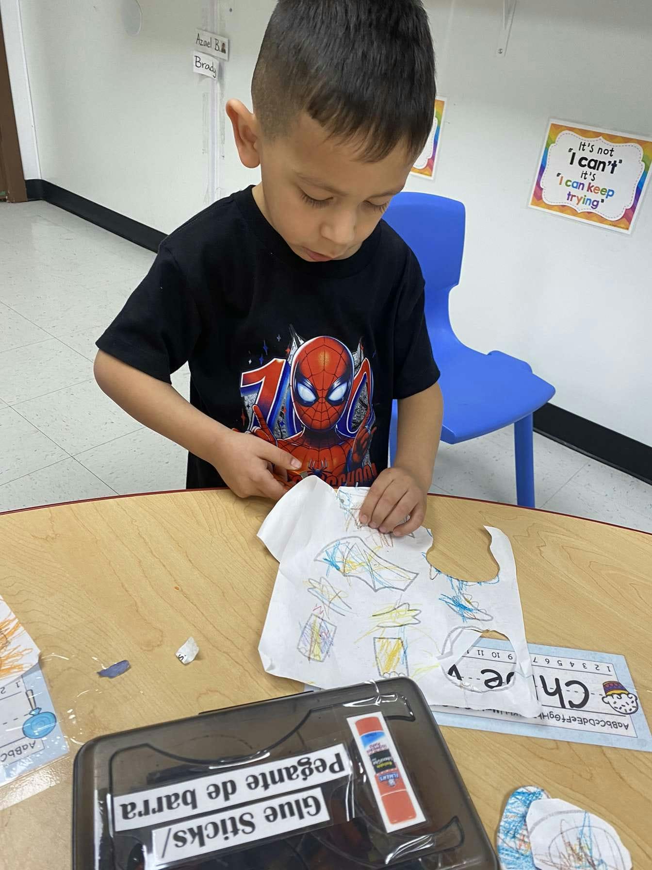 Child in a black shirt working on a craft at a table