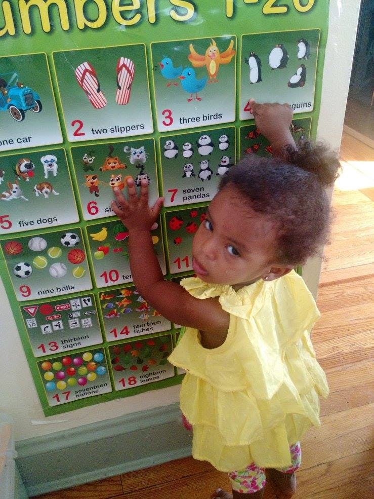 Child touching a numbers chart
