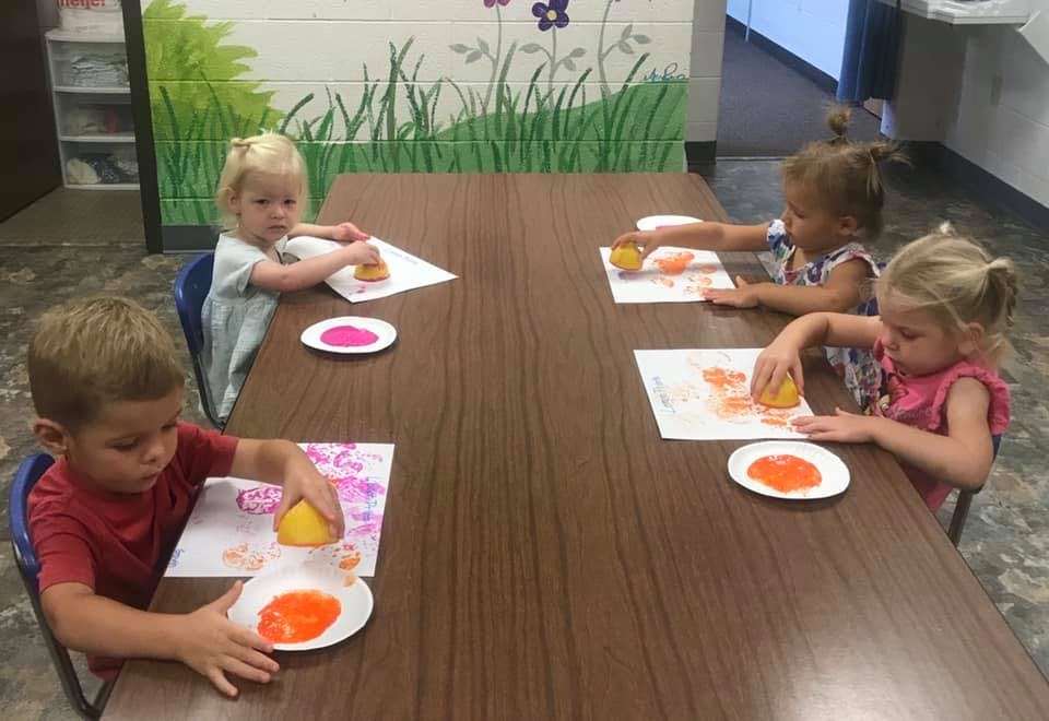 Four children at a table doing sponge painting