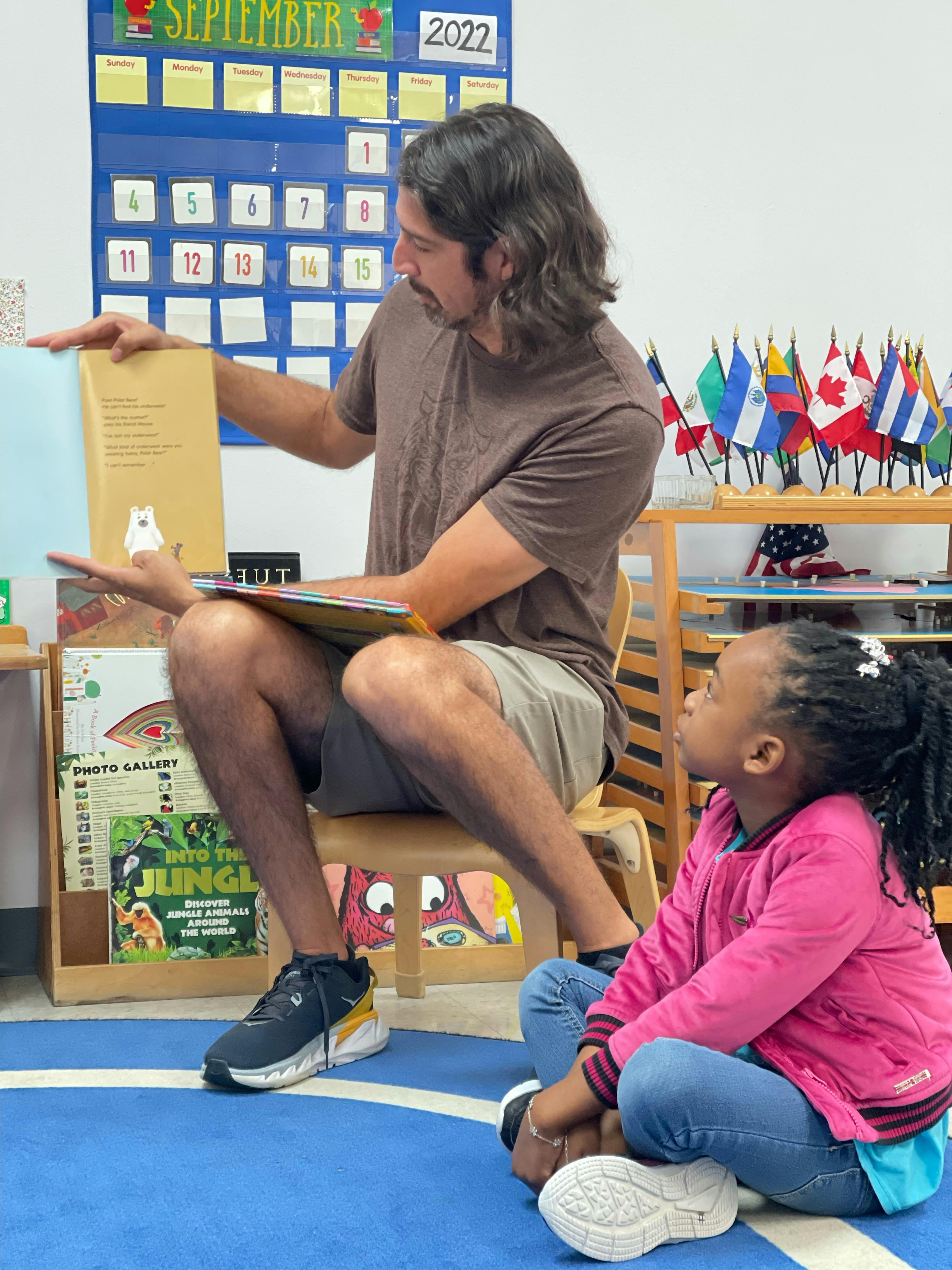 Person reading a book to a child in a classroom