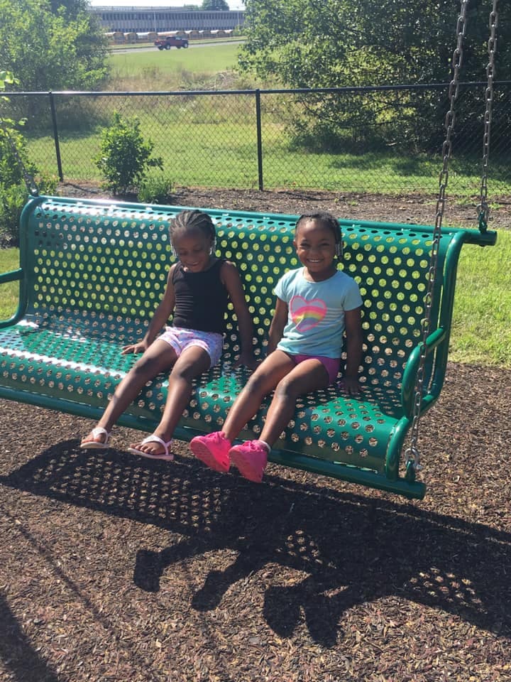 Two children sitting on a green swing
