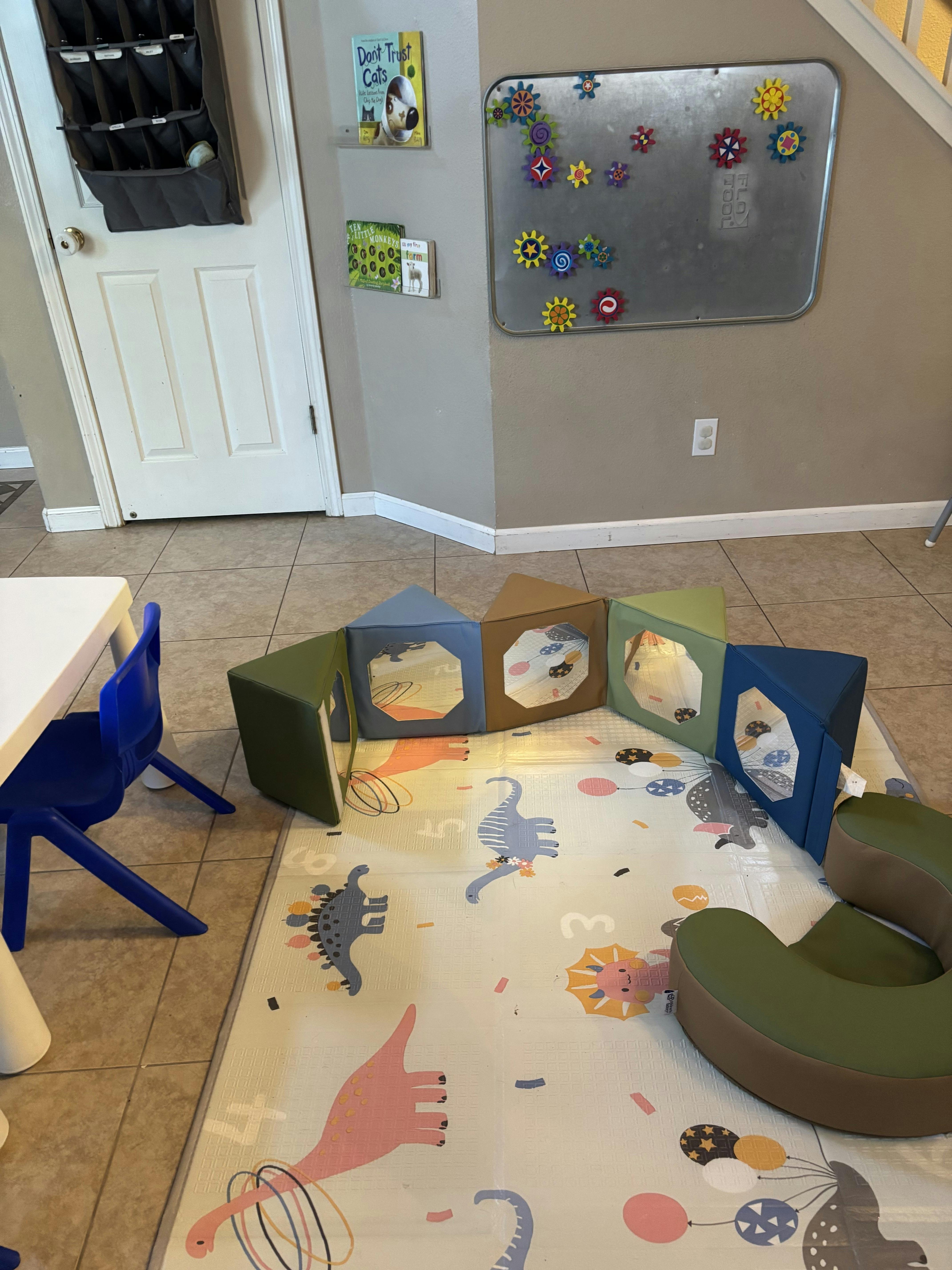 Playroom with soft play blocks, dinosaur rug, and magnetic board