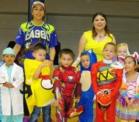 Two adults and multiple children in costumes