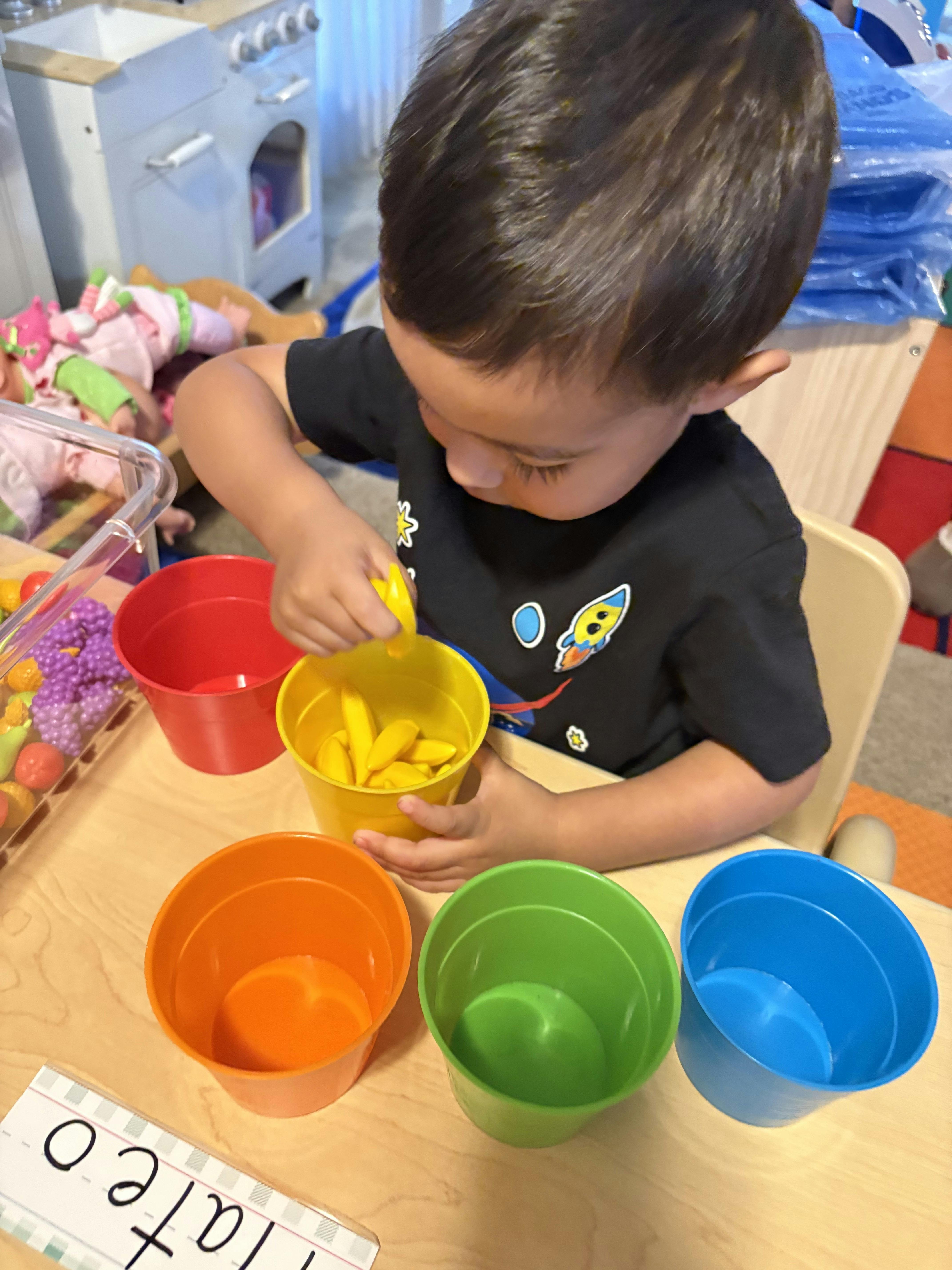Child playing with colorful cups and small yellow objects