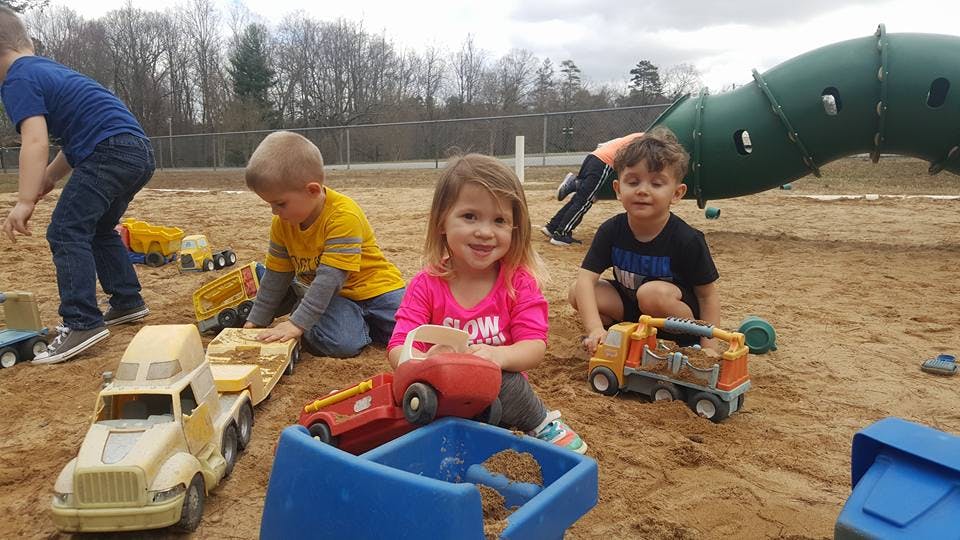 Children playing with toy trucks in a sandbox