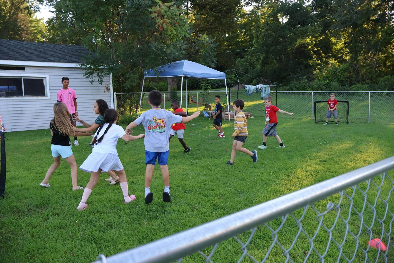 Group of children playing a game in a grassy backyard