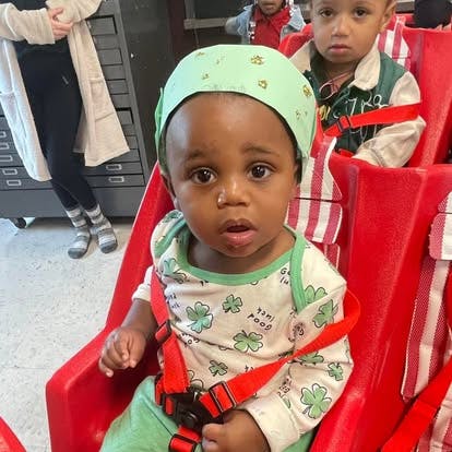 Child in a red seat with a green hat