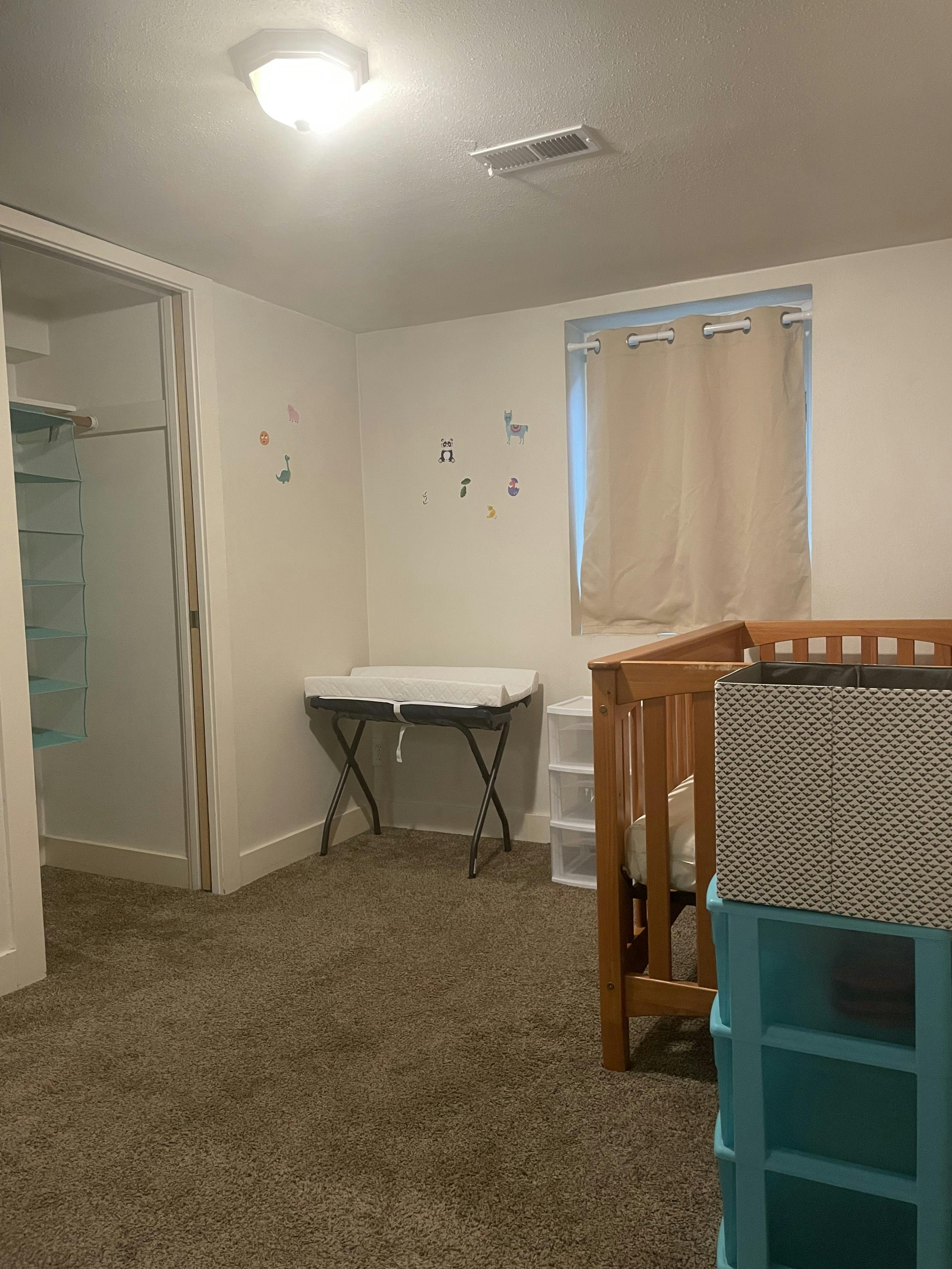 Baby's room with a changing table, crib, window, and closet