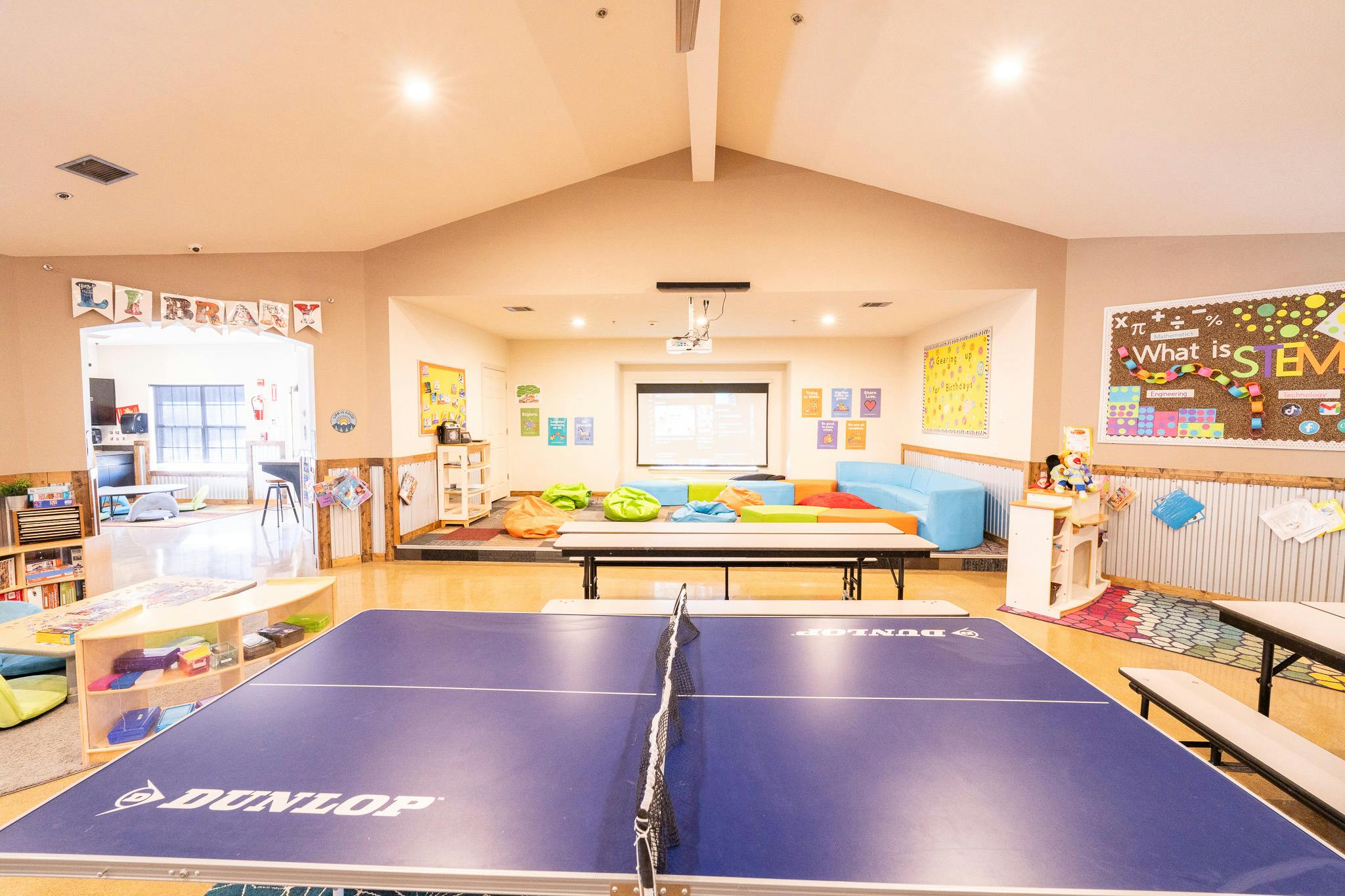 Ping pong table in a classroom with bean bag chairs and a STEM poster