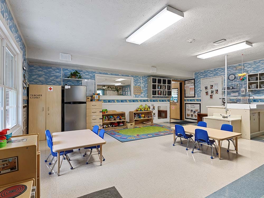 Classroom with small tables and chairs, a teacher closet, and a changing station