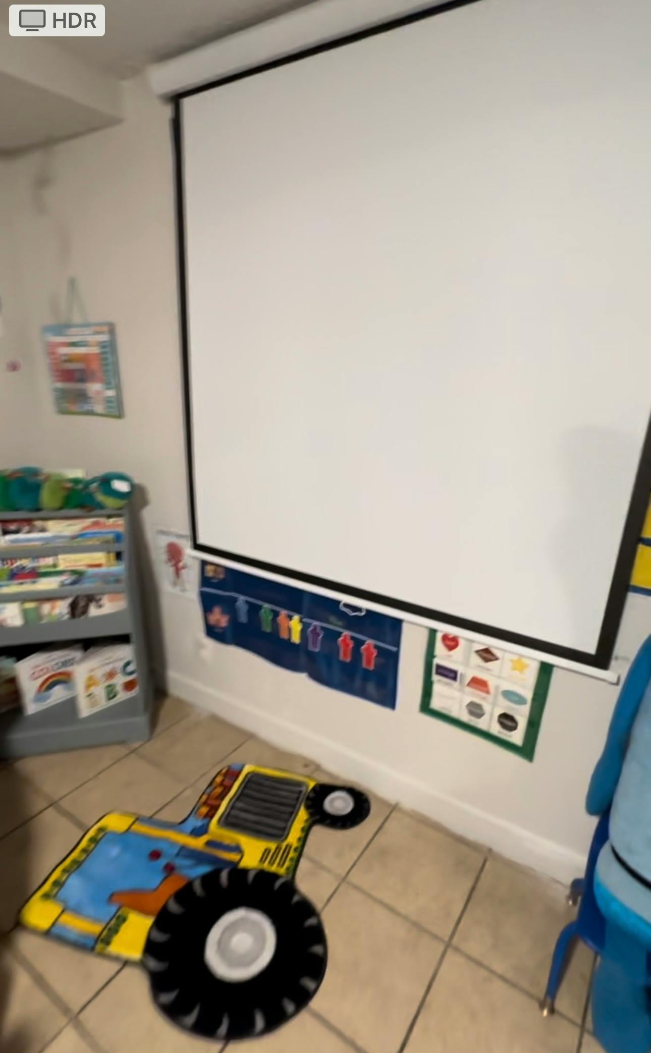 Projector screen in a classroom with a tractor rug on the floor