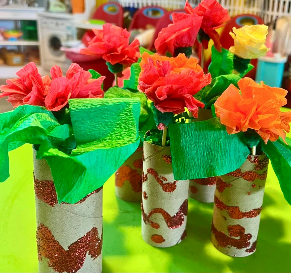 Handmade paper flowers in decorated cardboard tube vases