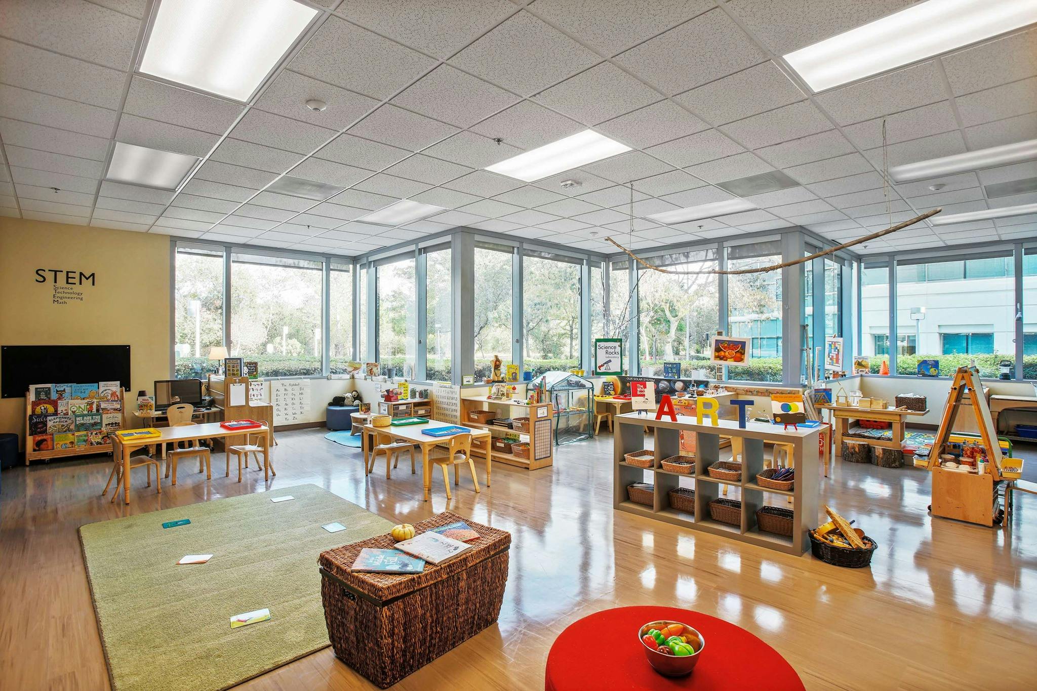 Empty classroom with small tables, chairs, and learning materials