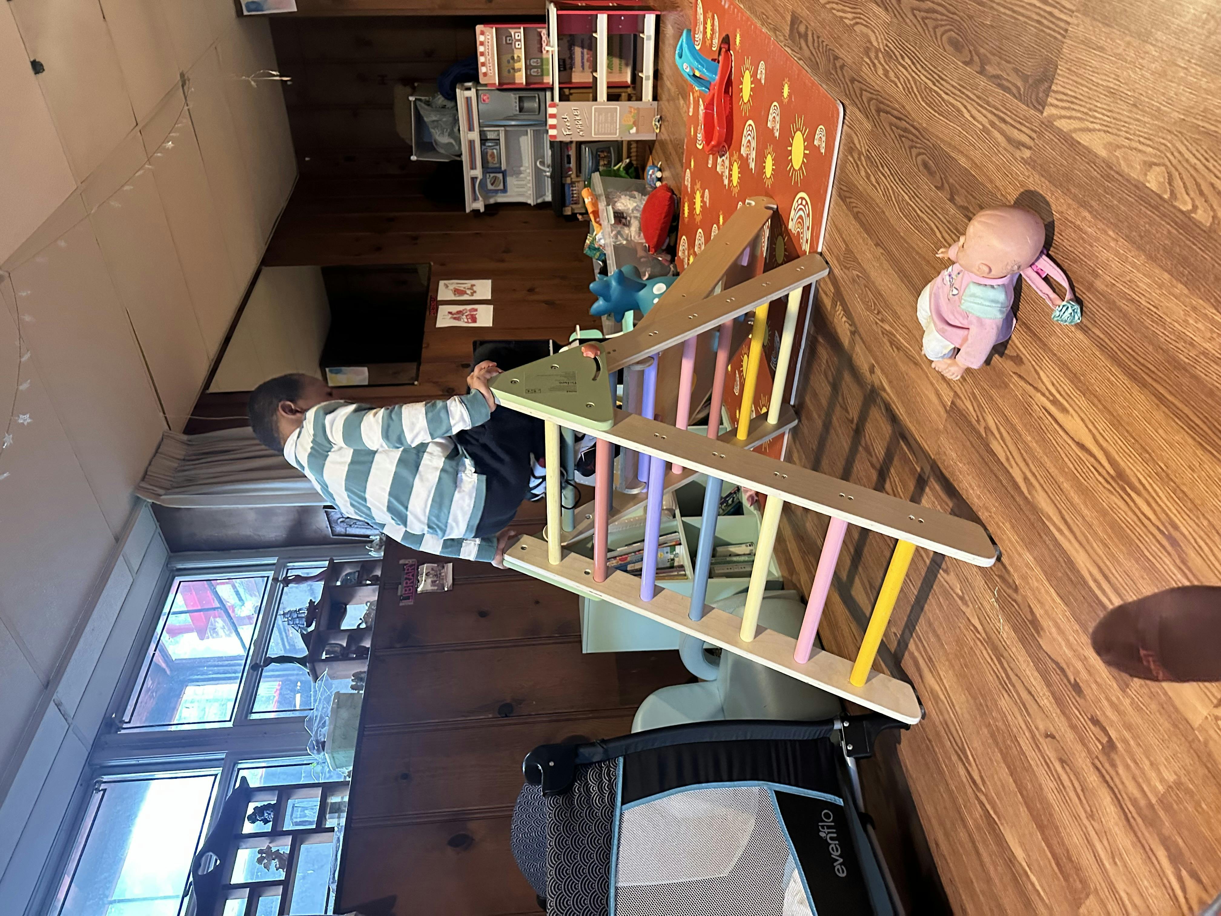 Child climbing on a wooden play structure with colorful rungs