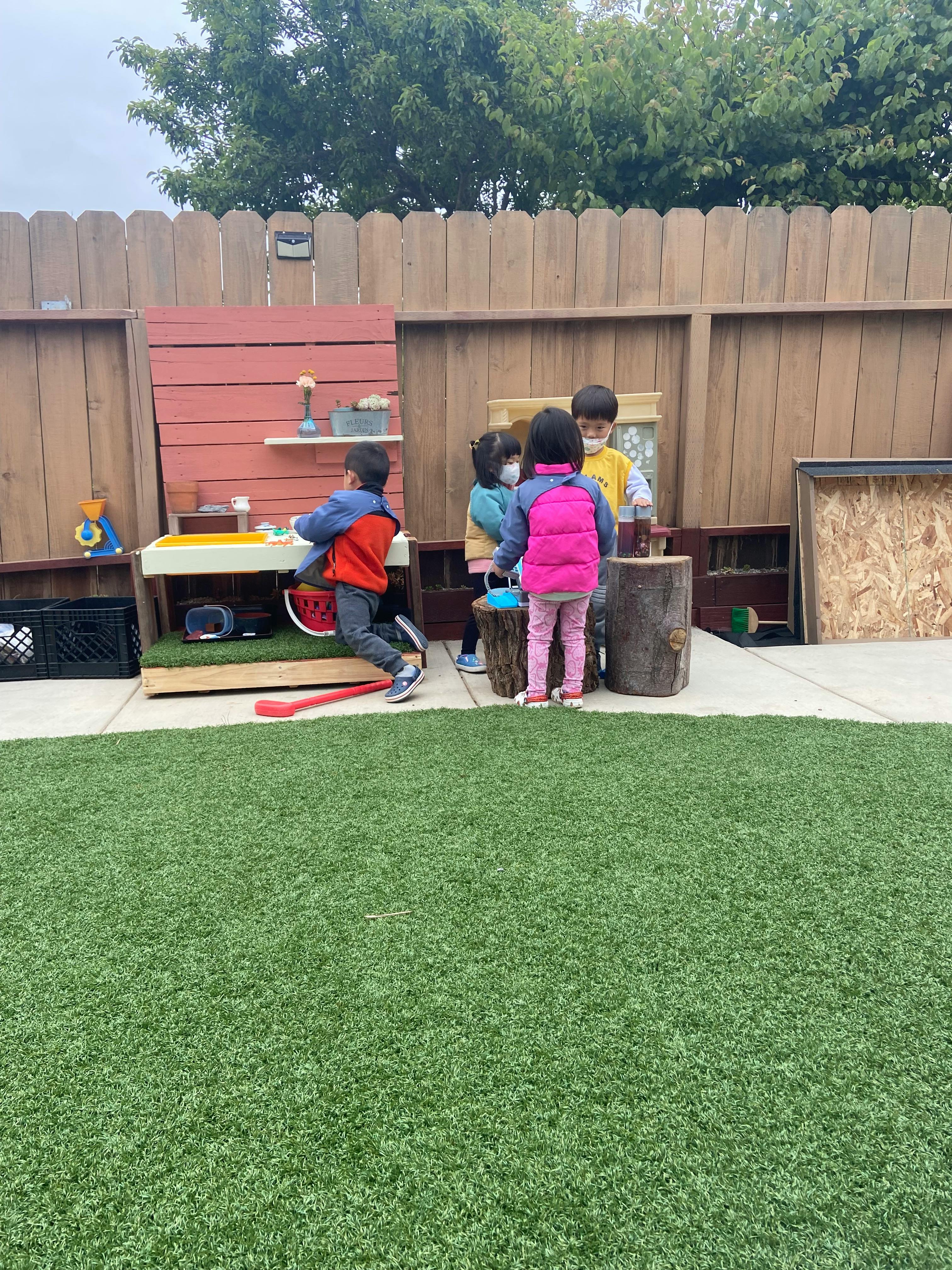 Children playing in an outdoor area with a wooden fence