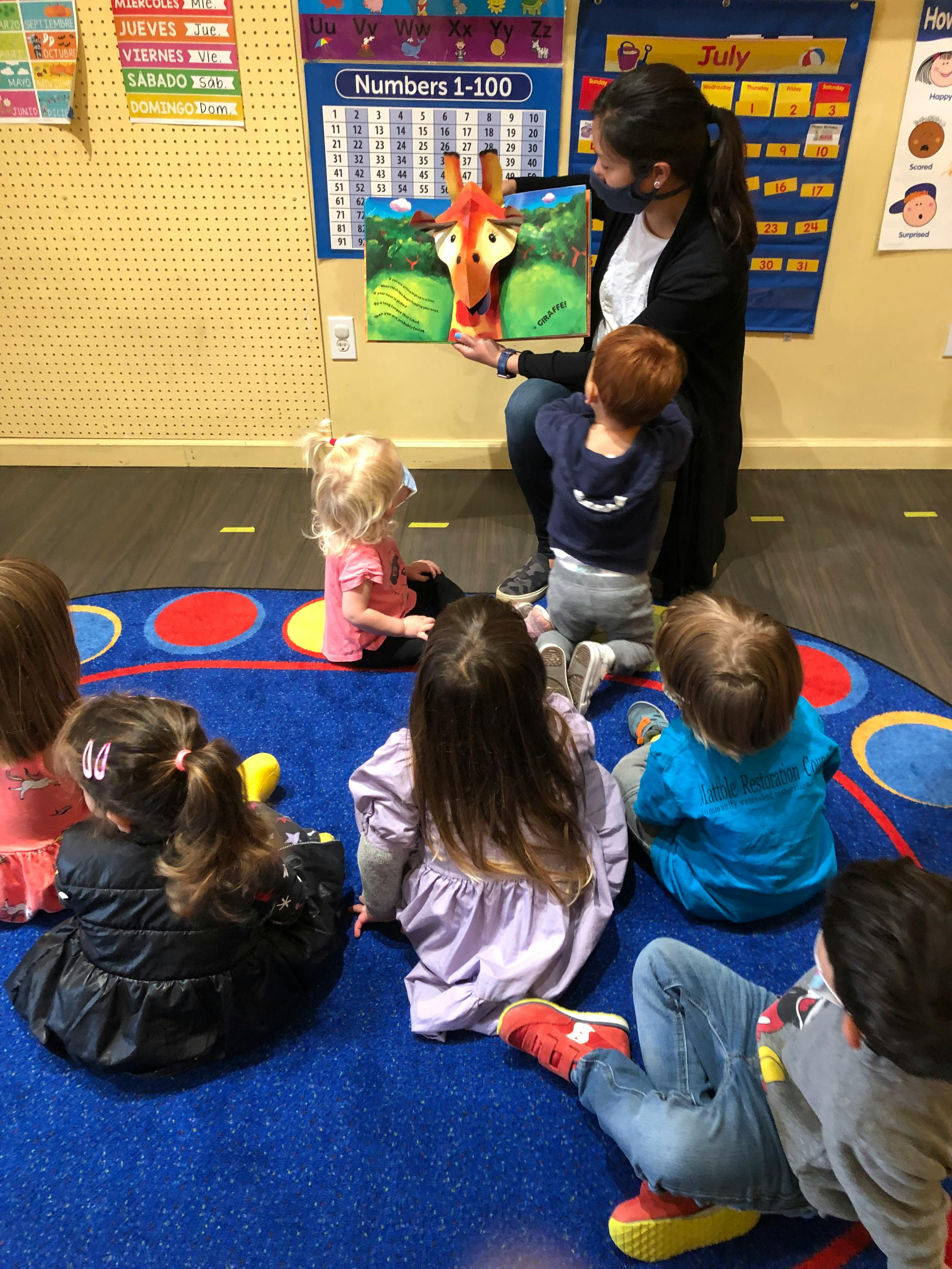 Person reading a book to children in a classroom