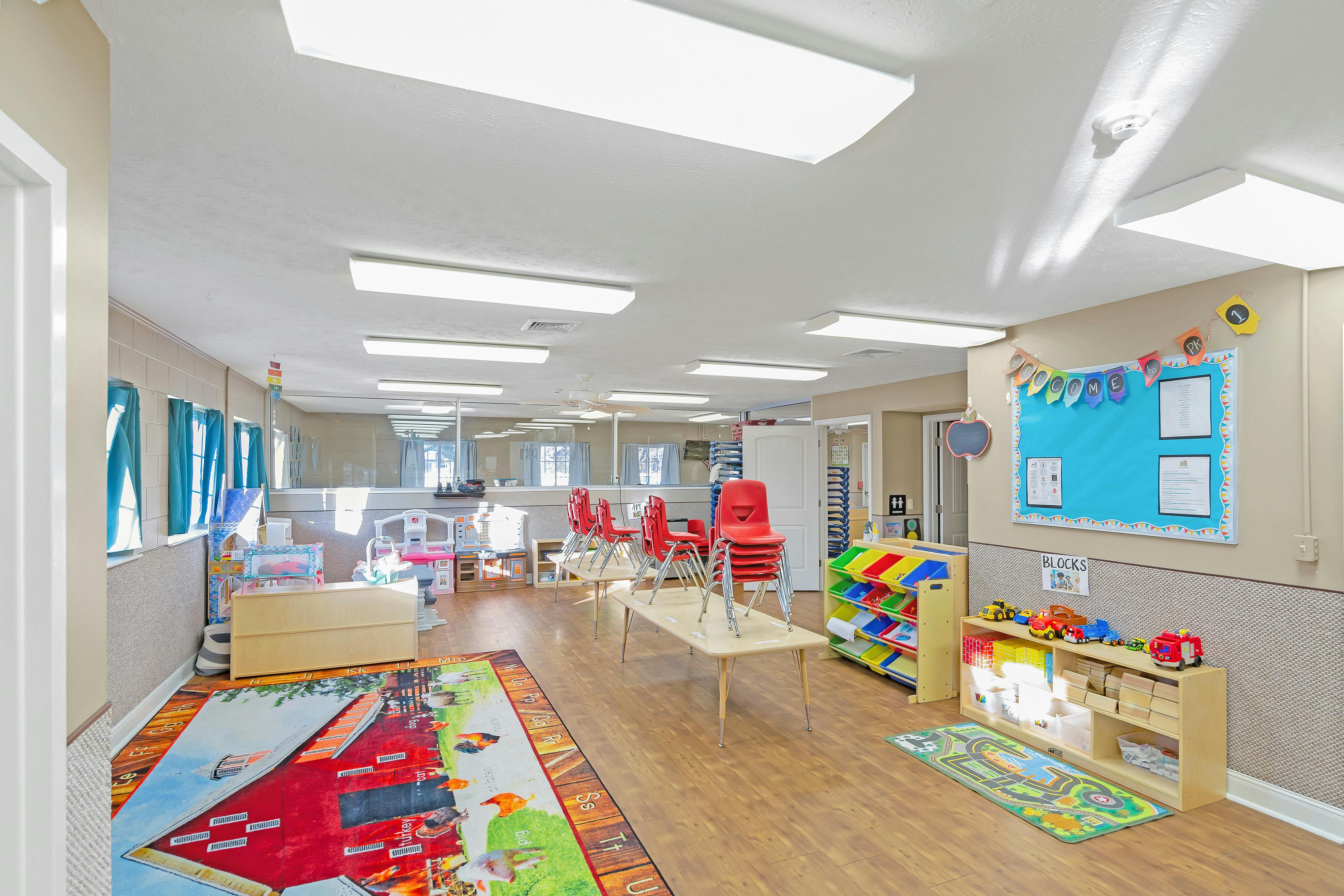 Classroom with tables, red chairs, and play areas