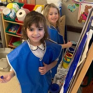 Two children in smocks painting at an easel
