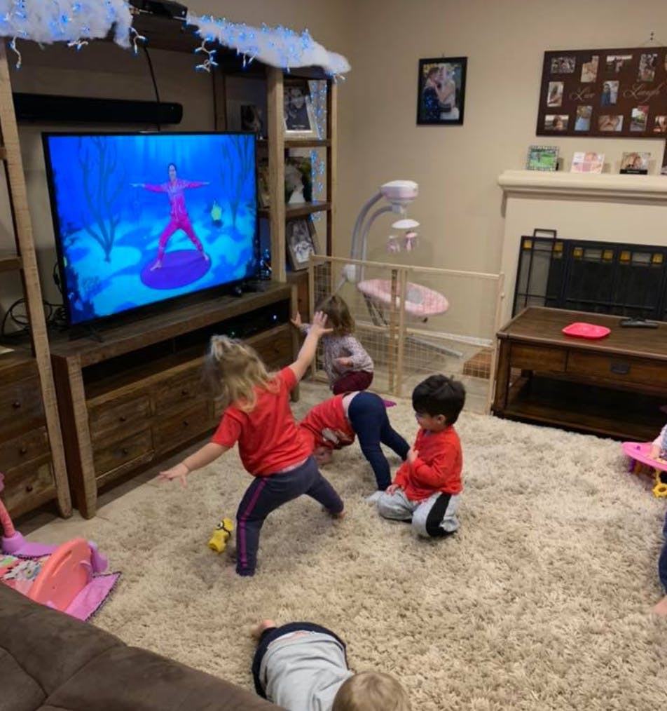 Children playing in a living room with a TV showing a video game