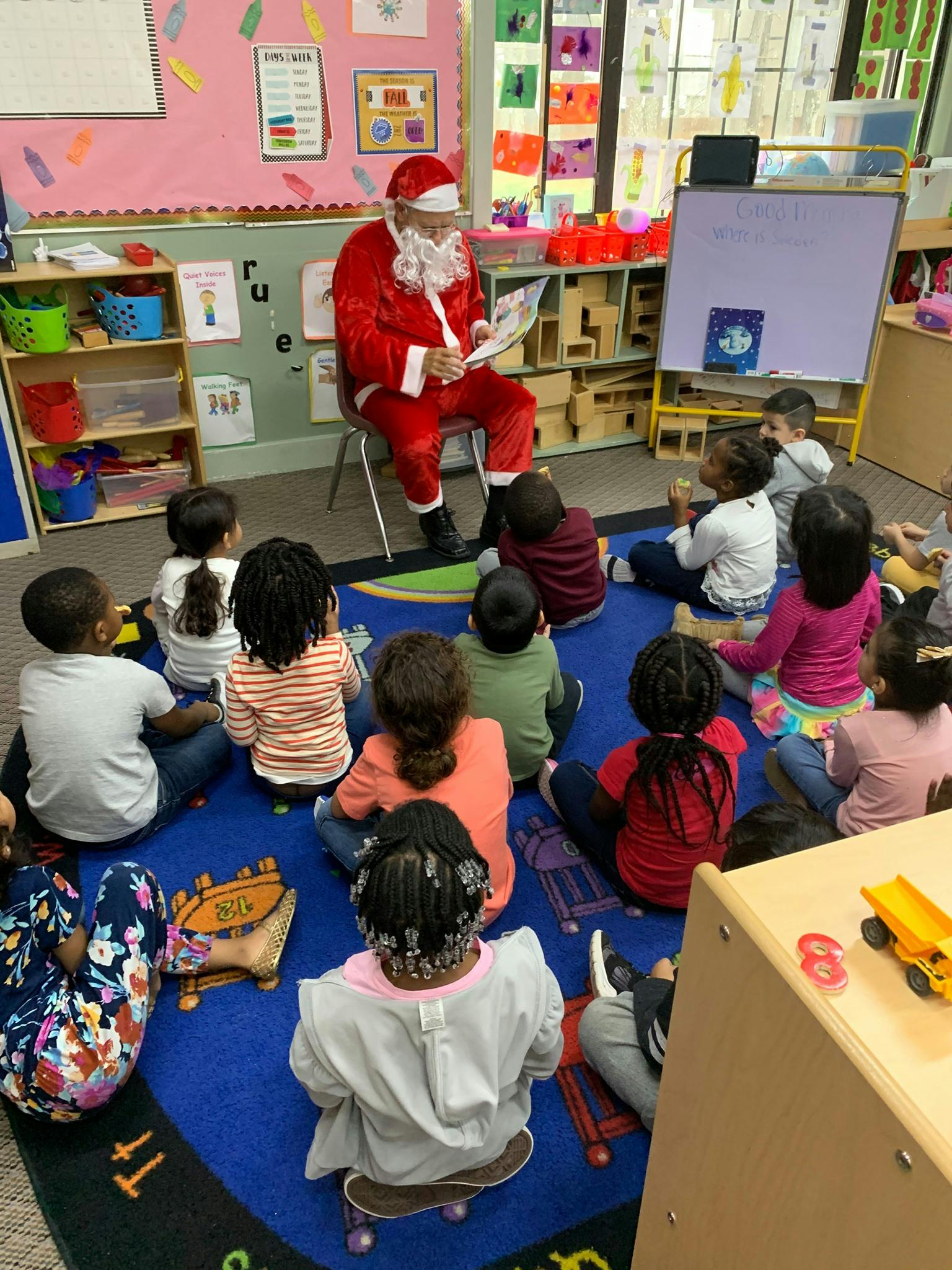 Person in Santa costume reading to children in a classroom