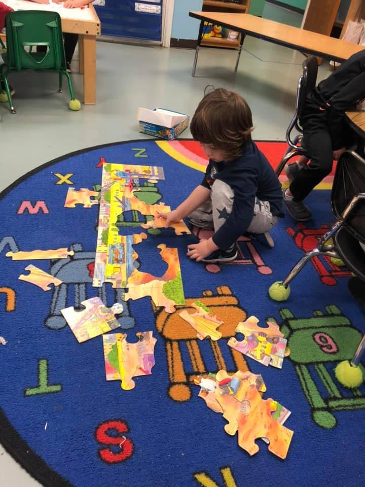 Child on a rug assembling a floor puzzle