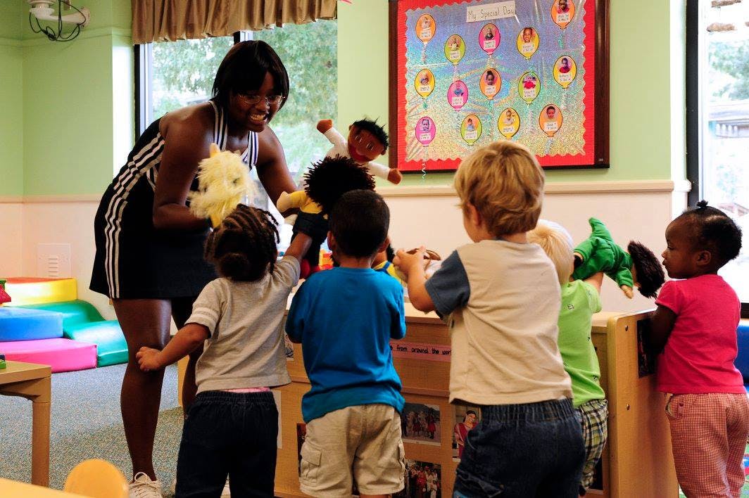 Person and children playing with puppets in a classroom