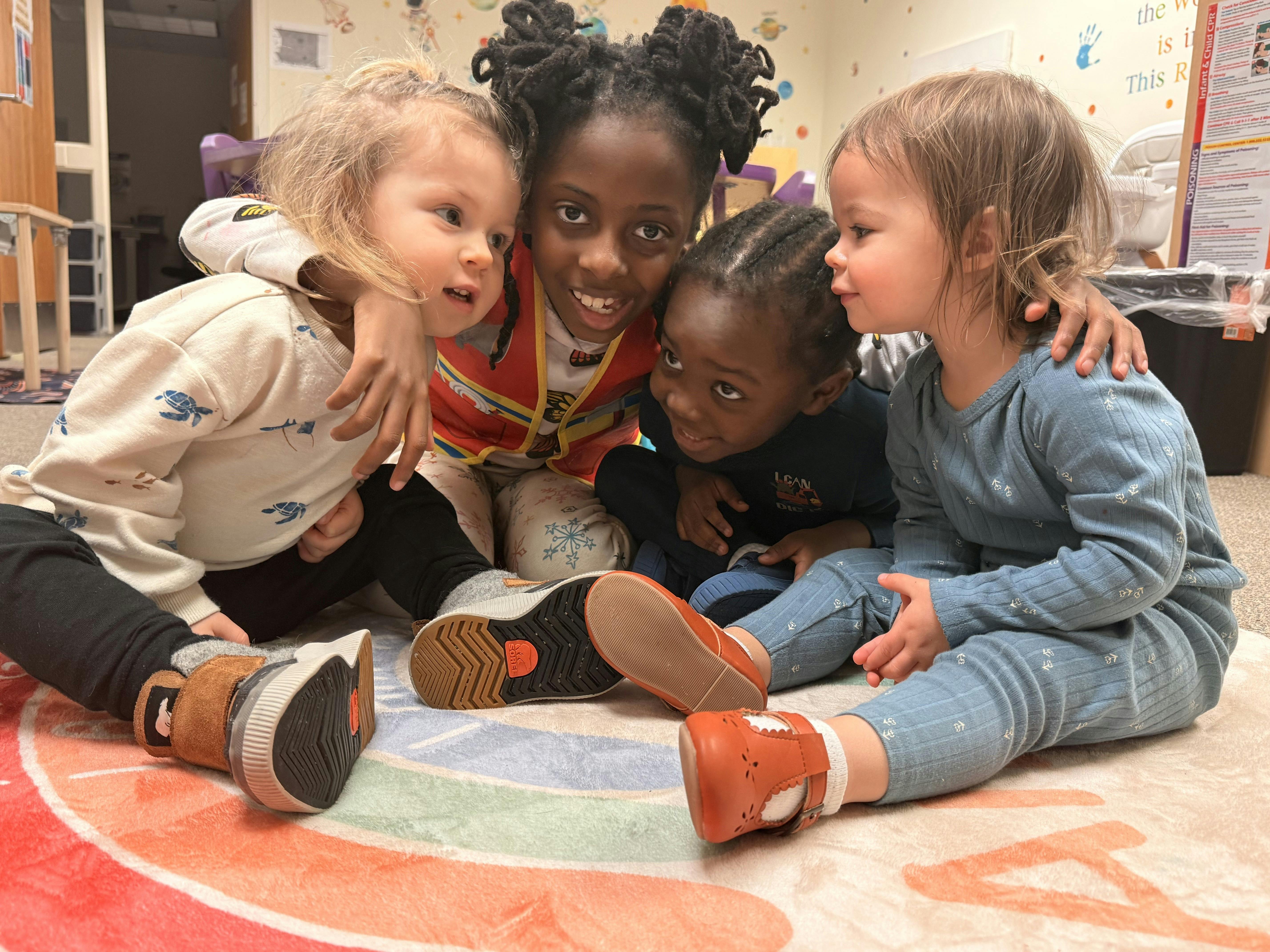Four children sitting together on a rug