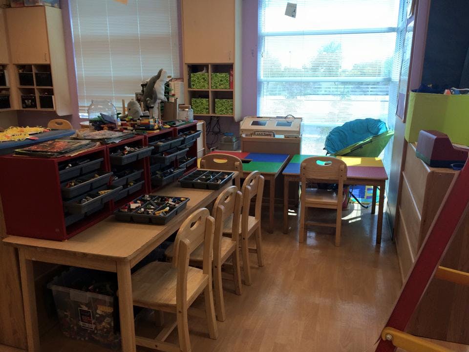 Classroom with tables and chairs, storage units, and a large window