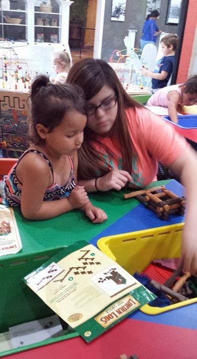Person and child playing with building blocks at a table
