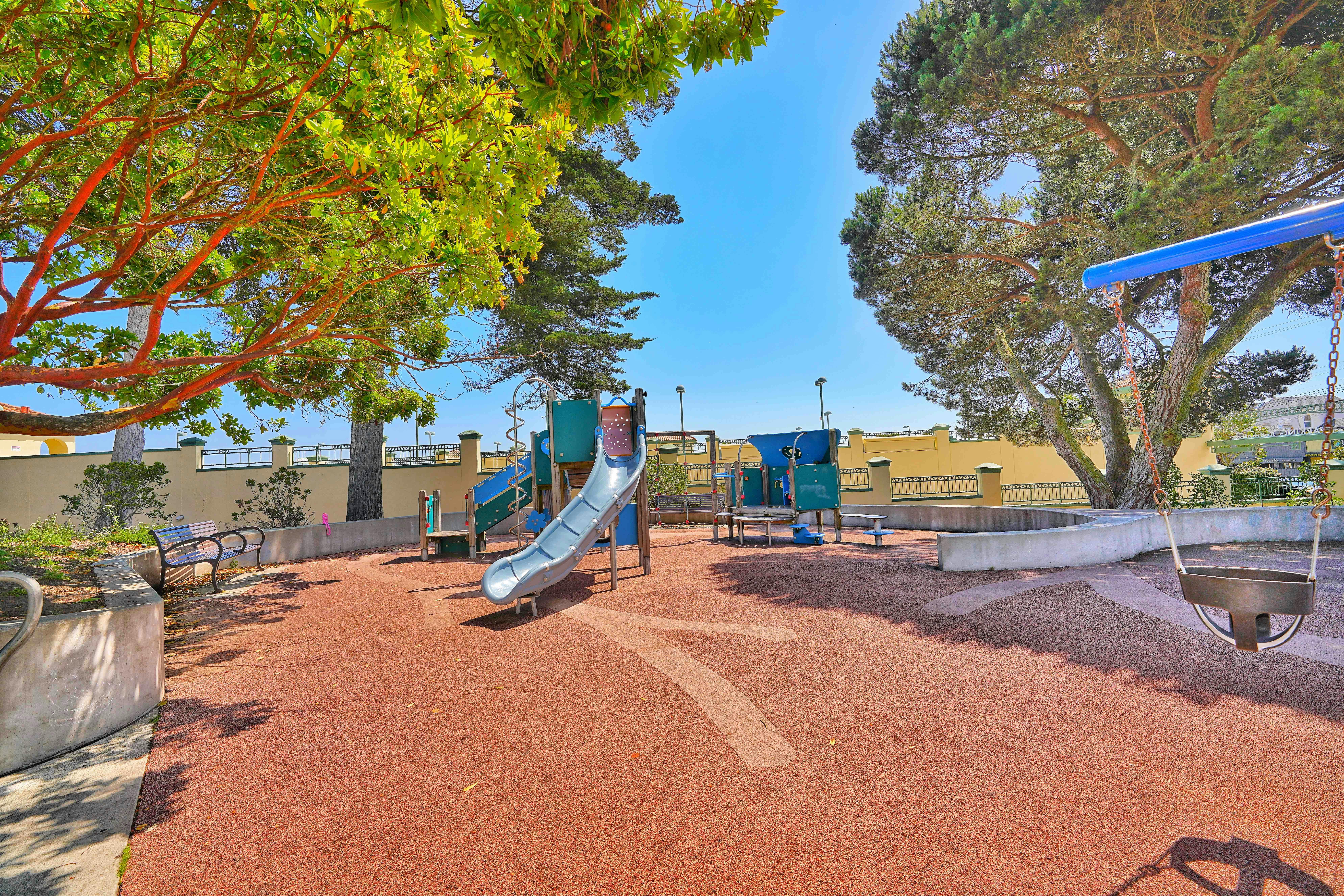 Playground with slides and a swing set surrounded by trees