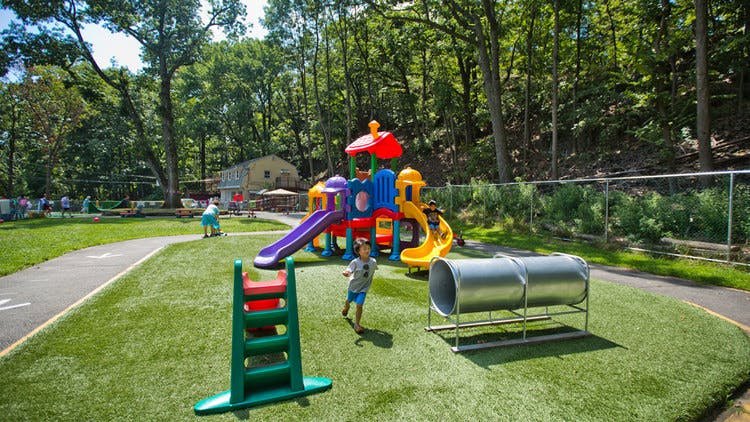 Child running on a playground with play structure and tunnel