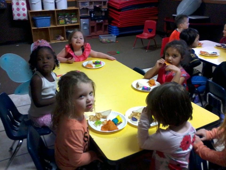 Children eating at a yellow table in a classroom