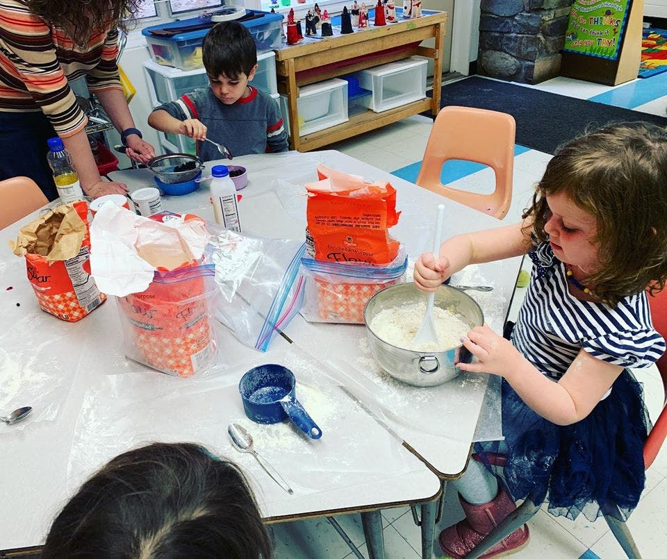 Adult and children at a table mixing ingredients in bowls