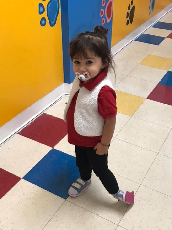 Child with pacifier standing on a checkered floor