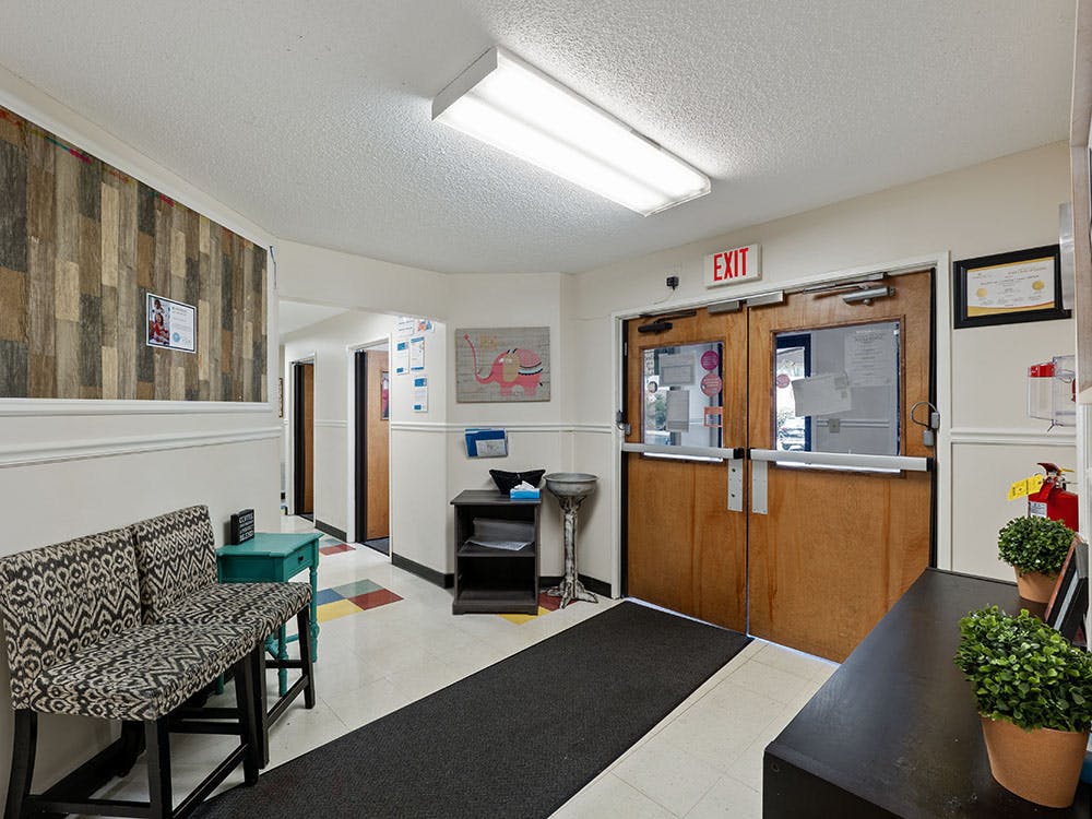 Lobby area with double wooden exit doors, a patterned bench, and a textured wall