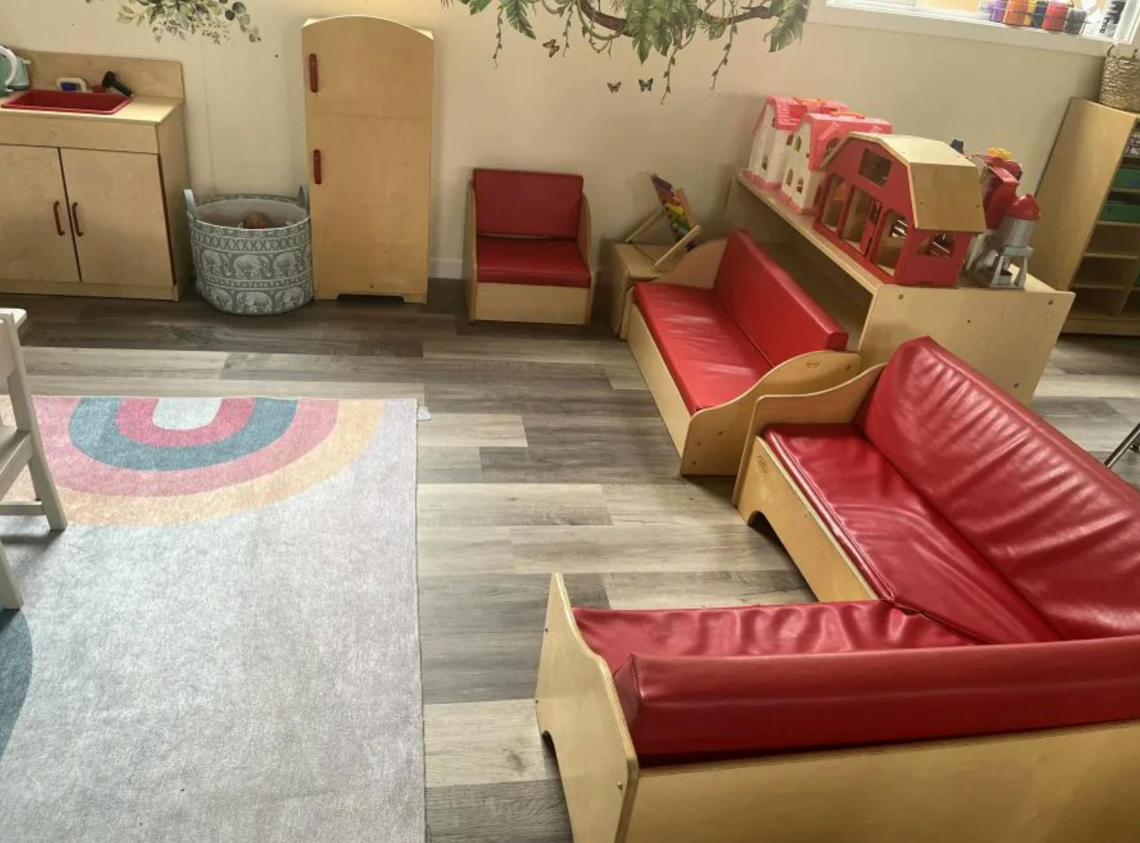 Childcare room with wooden furniture and red seating